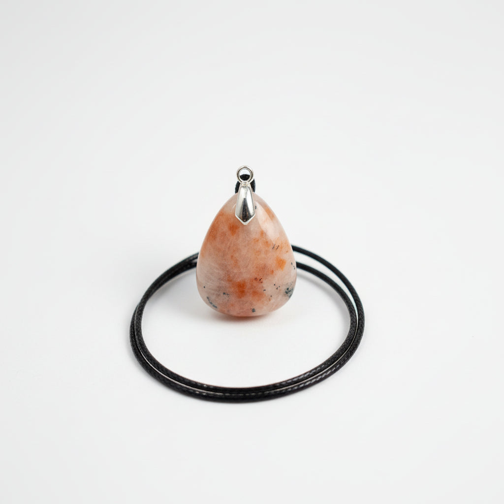 Pendente a goccia in Pietra del Sole naturale con cordoncino nero su sfondo bianco